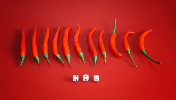 Chili peppers Yazıtı sıcak yanında kırmızı bir yüzey üzerinde — Stok fotoğraf