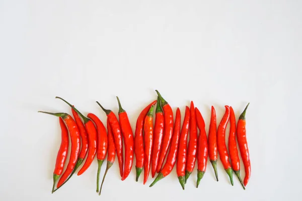 Baljor av röd chilipeppar ligga på en vit yta. Krydda och hälsosam mat. Fritt utrymme för inskriptioner. — Stockfoto