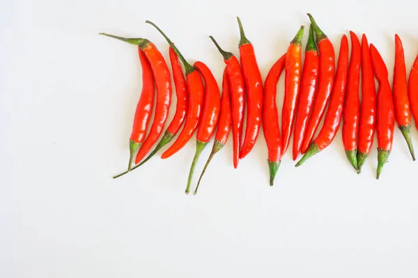 Pods av röd chilipeppar ligger på en vit ren yta. Smaksättning och hälsosam mat. Fritt utrymme för inskriptioner. — Stockfoto