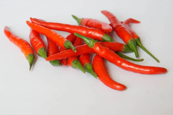 Las vainas de ají picante rojo se encuentran al azar en una superficie blanca. Condimento y alimentos saludables . — Foto de Stock