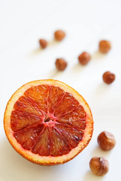Κόψτε το κόκκινο πορτοκαλί και τα φουντούκια στη λευκή διαγώνια επιφάνεια από τις ζωγραφισμένες σανίδες. — Φωτογραφία Αρχείου