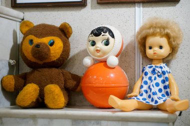 Eski vintage çocukların oyuncakları - bir bebek, bir ayı ve bir şöminenin üzerinde bir bardak.