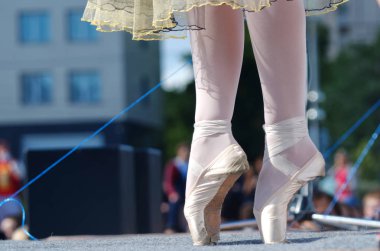 A young girl is standing on pointe on an outdoor street scene. clipart