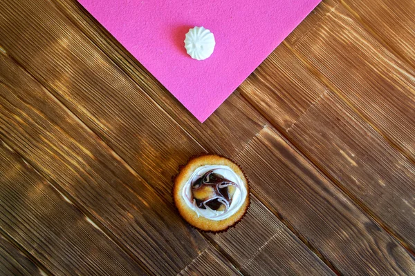 Z piniových prken se na stole obkulí ovocný dort a meringue. Minimalismu. Přírodní hnědé a růžové pozadí. — Stock fotografie