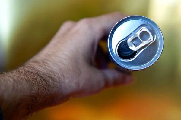 Male hand holding an open aluminum can of drink. View from above