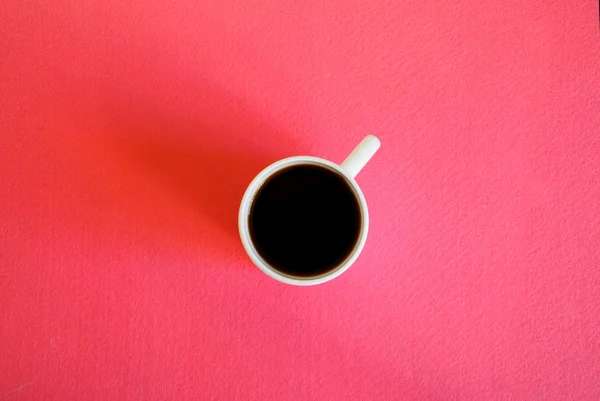 White mug with black coffee on a pink surface. View from above. — Stock Photo, Image