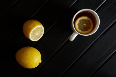 Siyah çay ve limon bir dilim ile beyaz kupa yanında duruyor