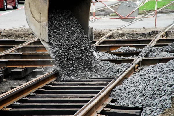 Excavator pours gravel on the tram rails. Repair the road. Urban