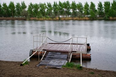 Yaz yağmuru sırasında göl veya nehir üzerinde küçük bir köy iskelesi