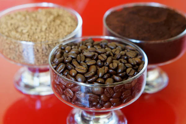 Three types of coffee in glass bowls on a red background: roaste