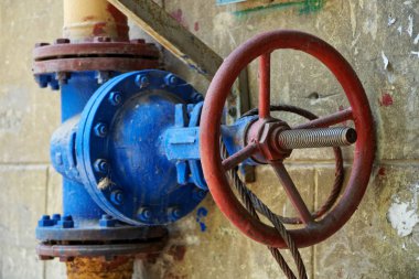 Bir duvar boyunca çalışan bir boru hattında büyük bir eski gaz valfi