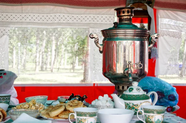 Samovar, belyashs y galletas dulces sobre la mesa en una tienda de campaña instan —  Fotos de Stock