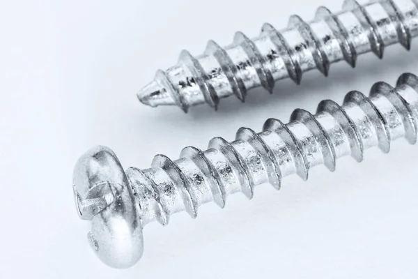 Two metal screws on a light surface. Close-up. Black and white t — Stock Photo, Image