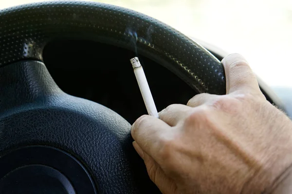 The driver smokes behind the wheel of a car during a traffic jam