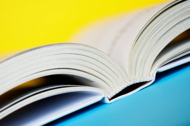 Açık bir kitap veya günlük sarı ve mavi arka plan üzerinde yatıyor. Clos