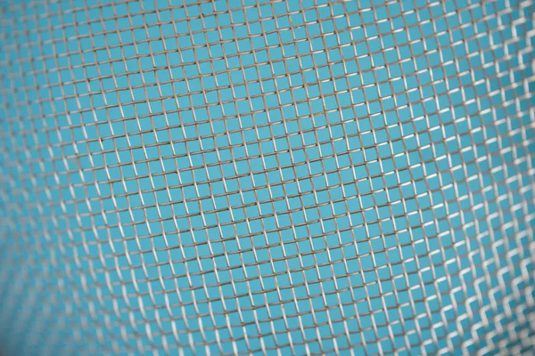 Объемный фрагмент плетения грязной металлической сетки на синем бэкгре — стоковое фото