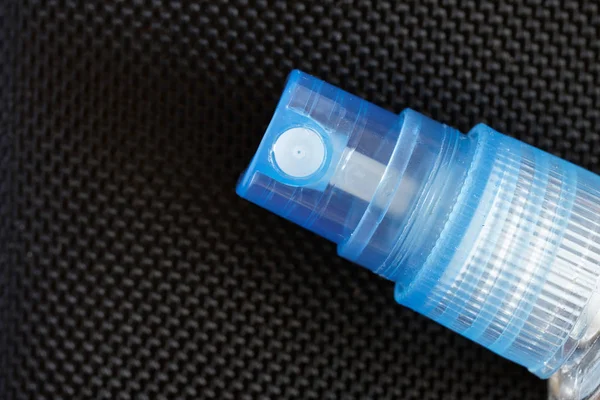 Blue plastic spray nozzle with perfume pump. Black textured back — Stock Photo, Image