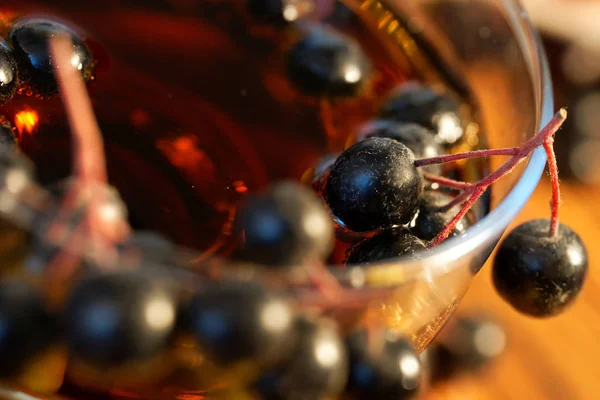 Des grappes de baies d'Aronia sur le bord d'un verre à vin avec homem — Photo