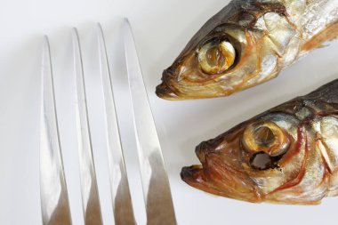 İki füme Baltık ringa balığı ve beyaz bir arka plan üzerinde bir metal çatal