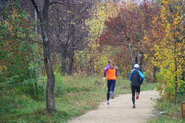 Sonbahar parkının arka sokağında koşan iki kız. Çalış, çalış.