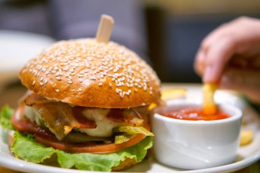 Bir sürü malzemesi olan büyük, lezzetli bir hamburger beyaz bir hamburgerin içinde. 