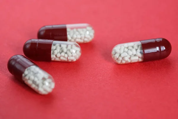 Διαφανείς κάψουλες χάπι με κόκκους βρίσκονται σε ροζ φόντο — Φωτογραφία Αρχείου