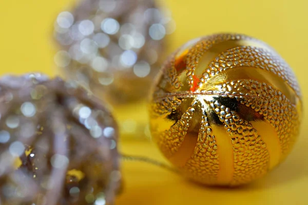 Shiny Christmas toys - balls lie on a yellow background. Prepari — Stock Photo, Image