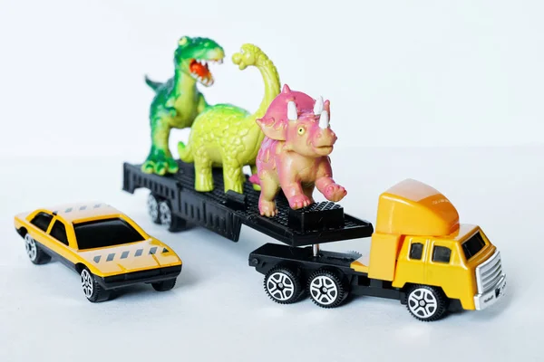 Een grote vrachtwagen en een auto vervoer dinosaurussen naar een natuurreservaat, — Stockfoto