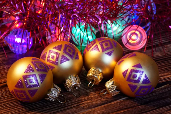 Golden Christmas decorations lie on a wooden rustic table next t — Stock Photo, Image