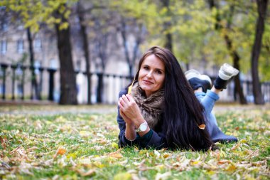 Uzun saçlı esmer bir kadın otobanda çimlerin üzerinde yatıyor.