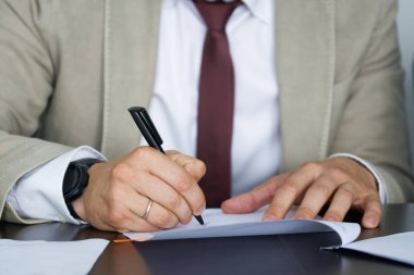 Açık takım elbiseli bir yetkili, avukat ya da yönetici bir belge imzalar. Yazışmaları yönetiyorum. Yakın plan. Yüzeyin derinliği. Yüzü yok