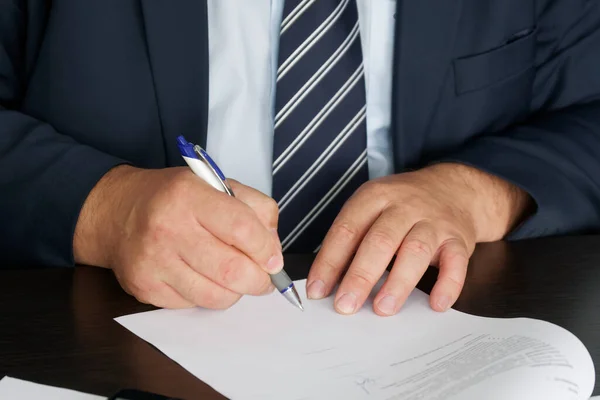 A manager, civil servant or lawyer in a dark suit signs a document. Conducting correspondence. Close-up. Shallow depth of field. No face