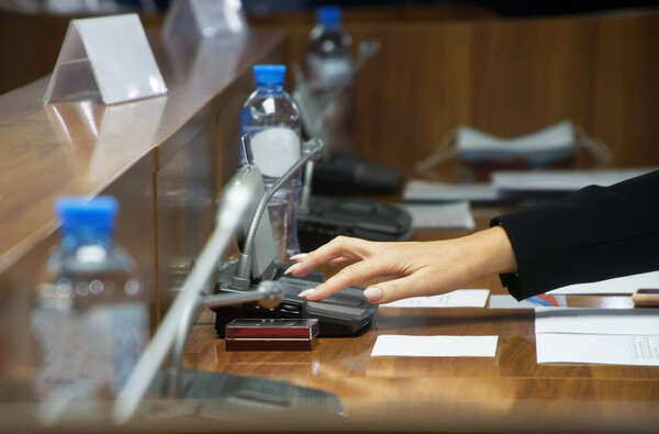 Hand of a woman voting during a political meeting. Parliamentary lawmaking. Without a face.. Shallow depth of field