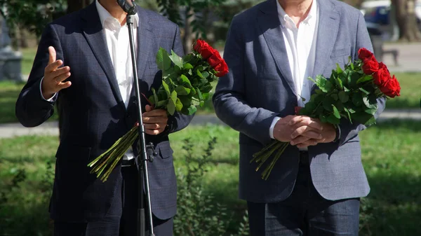 路上の公式イベントでは スーツ姿の役人2人とバラの花束が披露されます 顔はない — ストック写真