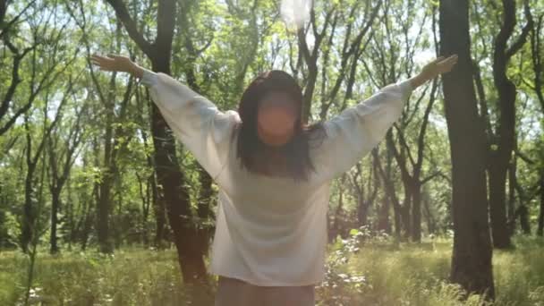 Frau hebt die Hände im sonnigen Wald, aus nächster Nähe. Entspanntes Lächeln. — Stockvideo