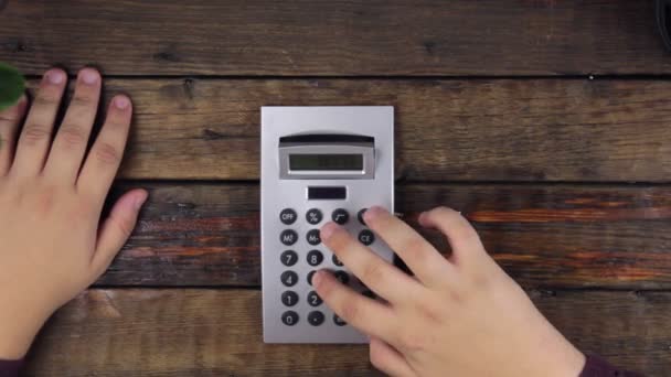 Top view, of businessman hand, count on a calculator examining display with magnifying glass. — Stock Video