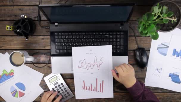 Felülnézet. Üzletember elemzi a diagram adatai, és kiszámítja a nyereséget a számológép. — Stock videók