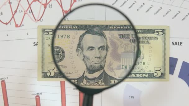 Изучение банкноты пять долларов, увеличивающейся с помощью увеличительного стекла . — стоковое видео