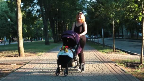 Mamma med barn, liggande i en barnvagn på en kvällspromenad. Urbana landskap. — Stockvideo