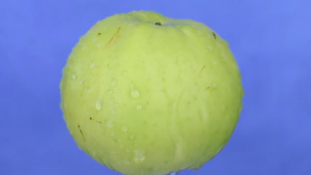 Gotas de lluvia cayendo sobre una manzana verde giratoria. Aislado — Vídeo de stock