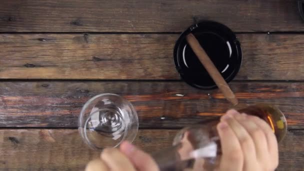 El hombre toma una botella y vierte alcohol en un vaso . — Vídeos de Stock