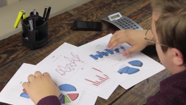Бизнесмен анализирует графики и рассчитывает на калькулятор . — стоковое видео