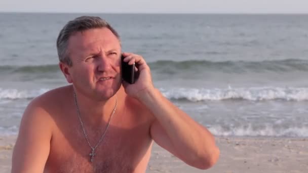 Χαμογελαστός άνθρωπος μιλάμε από το τηλέφωνο σε μια παραλία. — Αρχείο Βίντεο