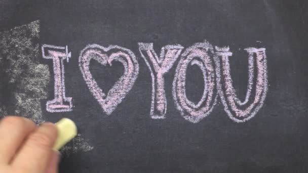 Small blackboard with the text i love you written on it in chalk. Stroke along the contour with chalk. — Stock Video