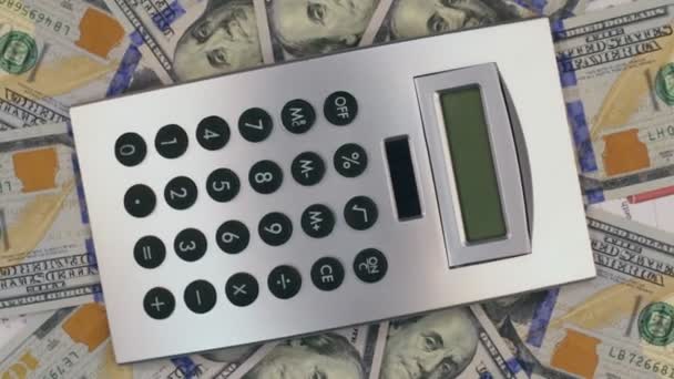 Rotação da calculadora deitado sobre os dólares. Vista de cima . — Vídeo de Stock