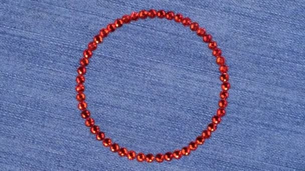 Rotación de un círculo hecho de pedrería roja, el símbolo del infinito. Vista superior . — Vídeos de Stock
