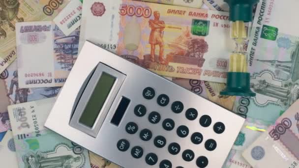 Kum saati ve hesap makinesi üzerinde ruble yalan dönüşü. Üstten görünüm. — Stok video