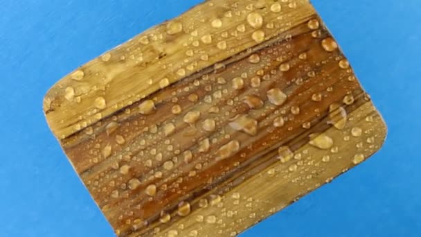 Wind blows water droplets off a rotating wooden frame. Isolated on blue background. — Stock Video