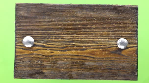 Σταγόνες νερού πέφτουν σε έναν σκοτεινό ξύλινο πίνακα με μπουλόνια σιδήρου. Απομονωμένη — Αρχείο Βίντεο