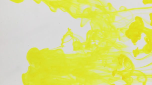 Gouttelettes peinture jaune dans l'eau sur fond blanc . — Video